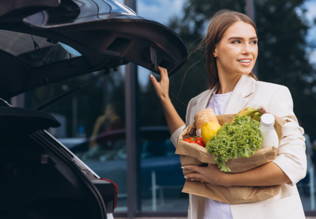 Young Woman Carries Groceries to Car With a Smile